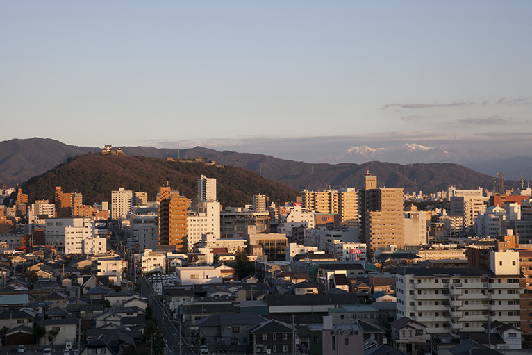 夕日に照らされて美しい松山城の遠景。遠くに石鎚山が見える。