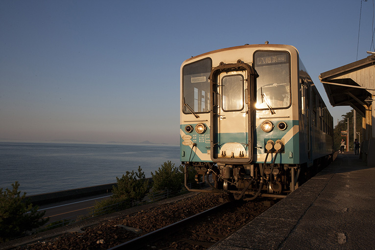 伊予灘の海と夕日に照らされた列車。